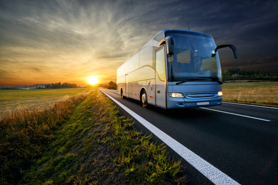 Agora dá para comprar passagem de ônibus pelo ChatGPT Bus traveling on the asphalt road in rural landscape at sunset